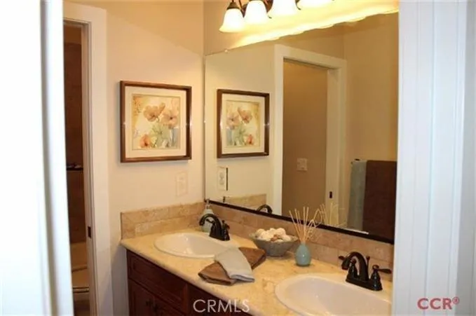 Hall bath with dual sink vanity and pocket door to separate bath/shower area.