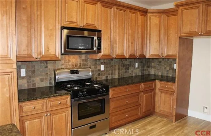 Stainless appliances, tiled backsplash and laminate wood floor.