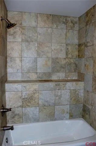 Hall bath has pocket door separating vanity from bath area. Tiled bath/shower with built in shelf.