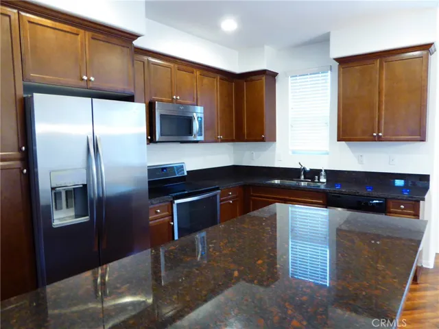 BEAUTIFUL GRANITE COUNTERS WITH WALNUT CABINETS & MATCHING STAINLESS STEEL APPLIANCES.