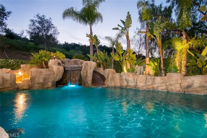 Boasting a premium, majestic, 10,000+ sq. ft, entertainer-loaded backyard offering a rock saltwater pool/spa with pebble-tech finish, waterslide, private grotto, pull-up, in pool bar seating, baja shelf and OUTDOOR kitchen with a built-in BBQ station, kegerator, warming drawer and gas burners!