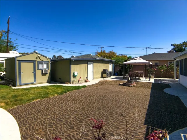 Backyard featuring a two-car garage, enclosed carport, and shed currently used as an office.