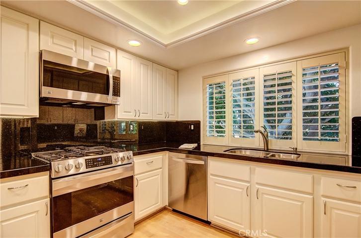 Remodeled chef's kitchen with stainless appliances and accents, stone counters and bright white cabinetry.