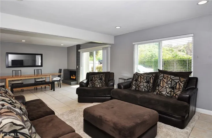 This picture shows the Living Room, Dining Room, Fire Place, the Double Pane Sliding Door, Double Pane Window, Recessed Lighting, and Tile Flooring.