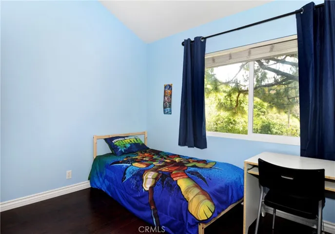 From this angle you see Desk, Bed, Wood Laminate Flooring, Double Pane Window peaking out to the Hills and with more room for more items in this spacious Bedroom.