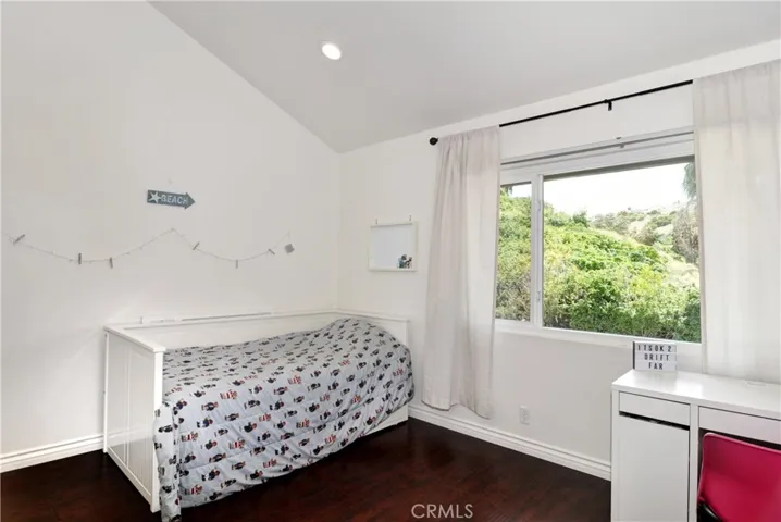 The Second Large Bedroom with Cathedral Ceilings, Wood Laminate Flooring, Double Pane Window peaking out to the Hills, Desk, and Recessed Lighting.