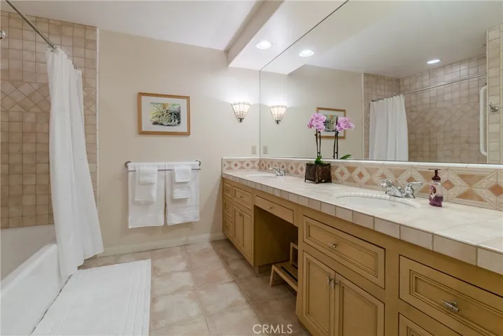 The adjacent full bathroom includes two sinks.