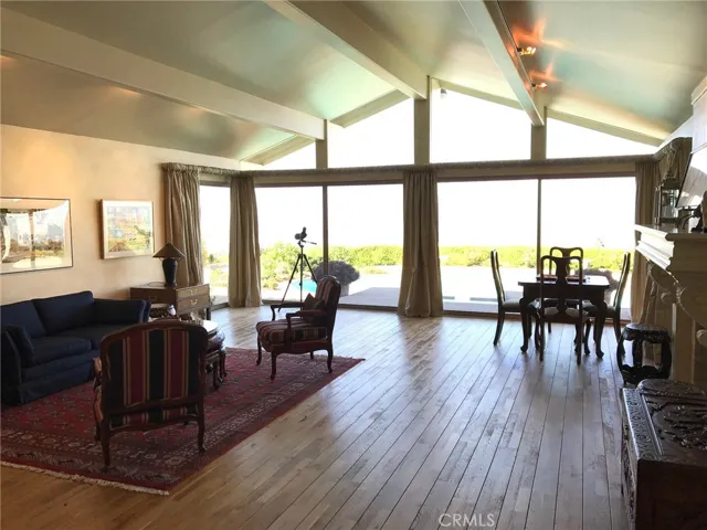 Another view of the living room with panoramic views, beautiful natural light, hardwood floors, and a fireplace.