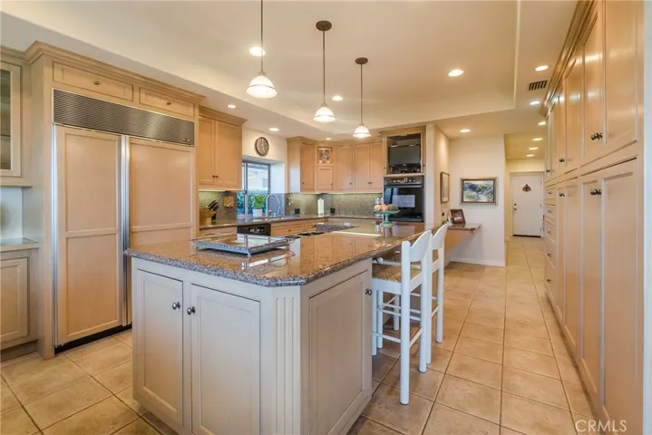 The kitchen includes a Sub-Zero refrigerator plus a warming drawer within the large island.