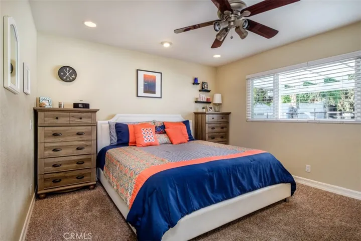 Large master bedroom with plush carpet and dual pane window looking out to the backyard.