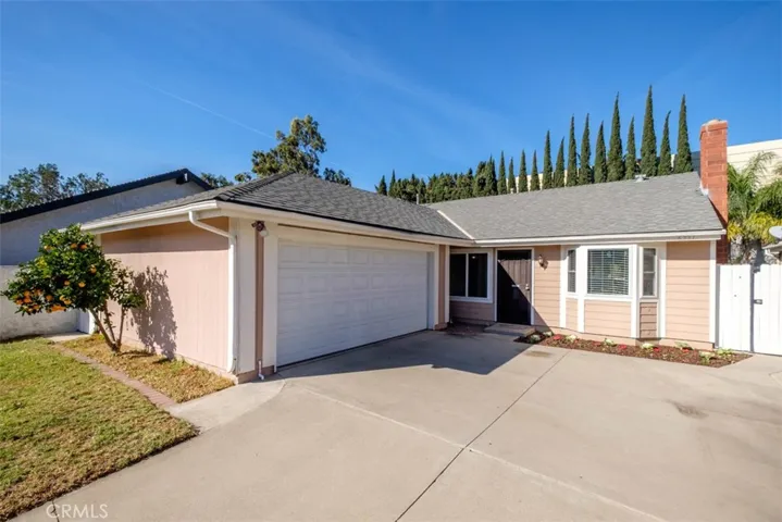 Front of home with orange tree and spacious driveway.