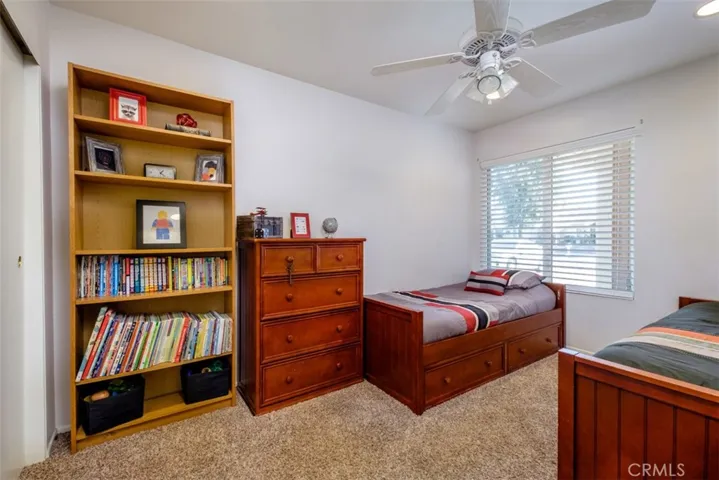 View of the second bedroom with plush carpet and ceiling fan.