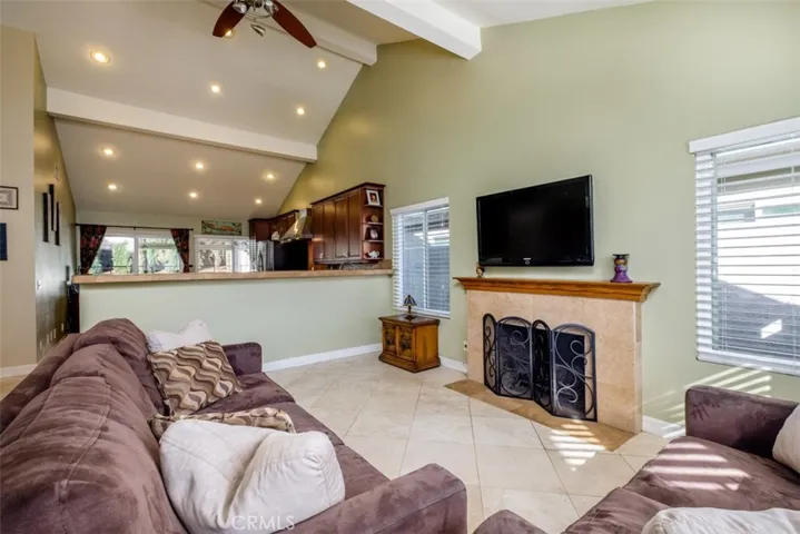 Open living room with vaulted ceiling, fireplace and counter top bar looking into the kitchen.