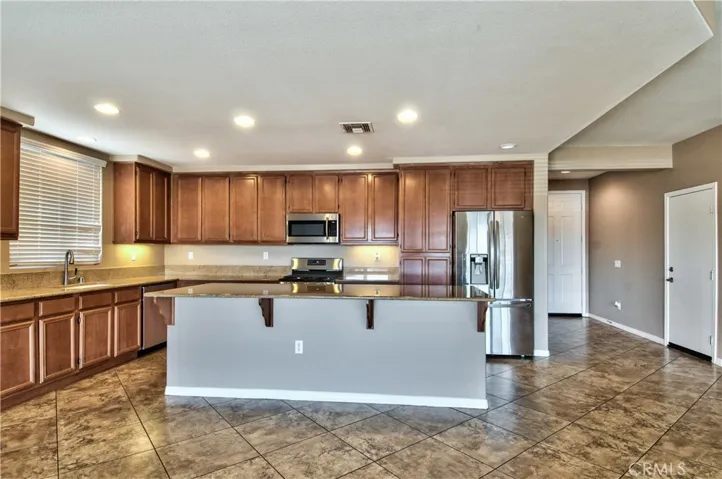 Large kitchen with island for meal preparation and seating. Granite countertops and stainless appliances.