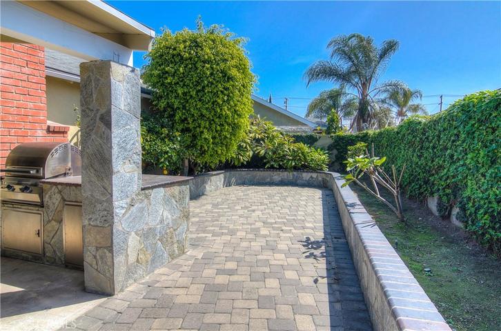 Outdoor kitchen with stainless accents is complimented by lovely stonework, pavers and raised planter areas.