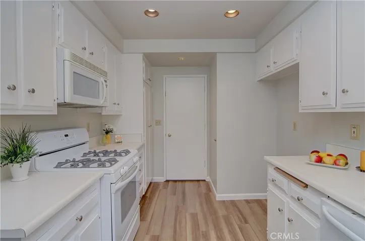 Gleeming kitchen with fresh white cabinetry and appliances, recessed lighting and plank flooring...big pantry and easy garage access too!
