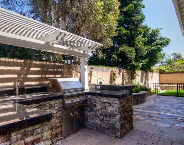 Complete outdoor kitchen has BBQ, sink and bar area.