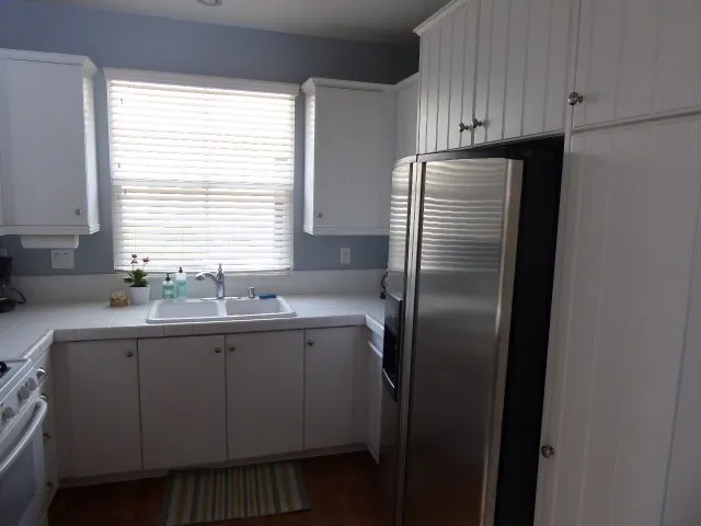 White shaker cabinetry and white ceramic tile make the kitchen glisten