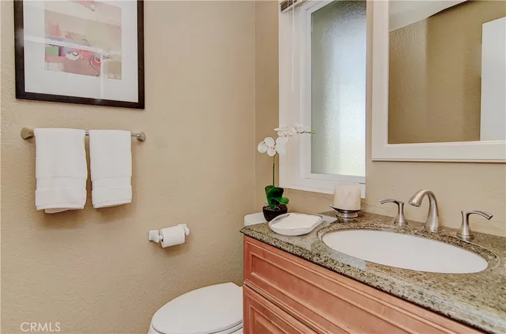 Tastefully remodeled downstairs powder room has brushed nickel accents and rich wood vanity.