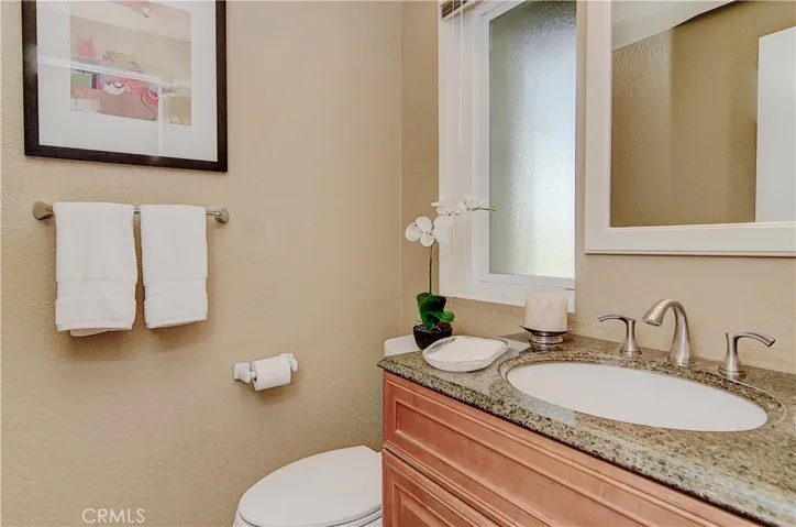 Tastefully remodeled downstairs powder room has brushed nickel accents and rich wood vanity.