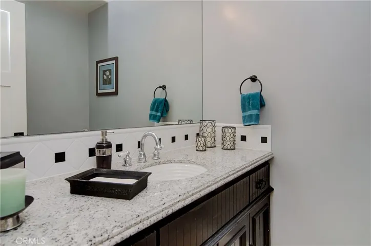 Downstairs power room has large vanity with stone counter and contemporary details.