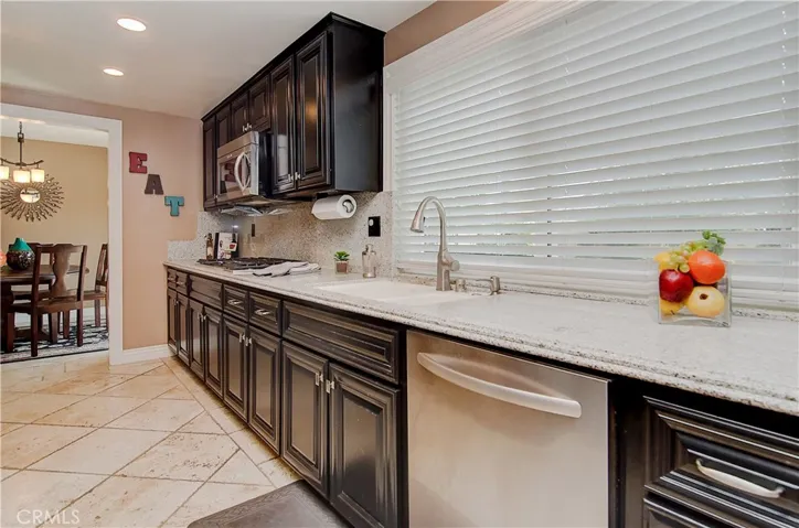 Gorgeous kitchen has rich wood cabinetry, stainless appliances, stone counters and loads of prep space.