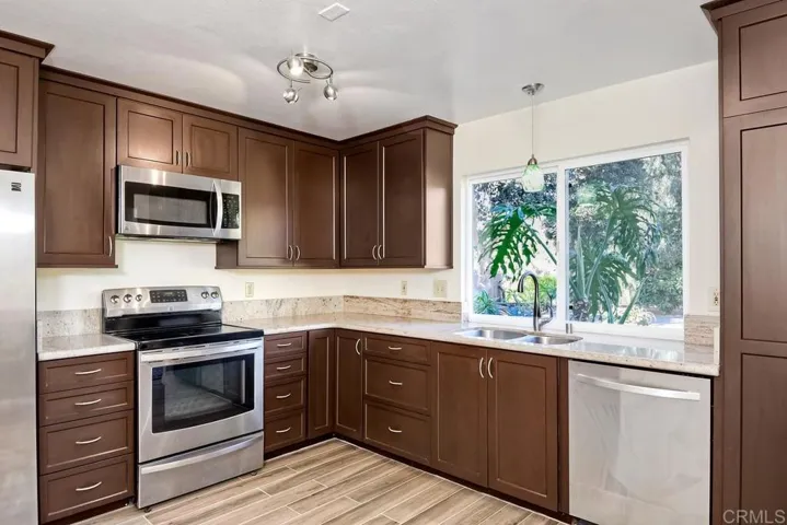 Updated kitchen with Stainless Steel appliances, new tile "'wood-look" tile floors!  Great light!  Pendant lights add some personality