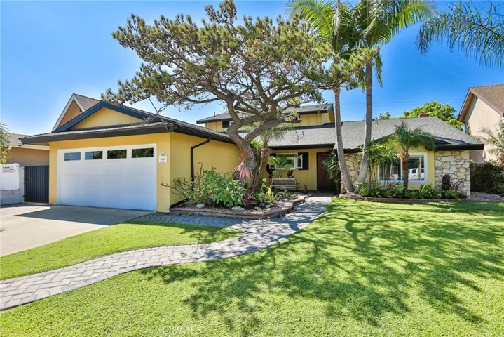 View from the street of this meticulously manicured home with swaying palm trees and tropical plants.