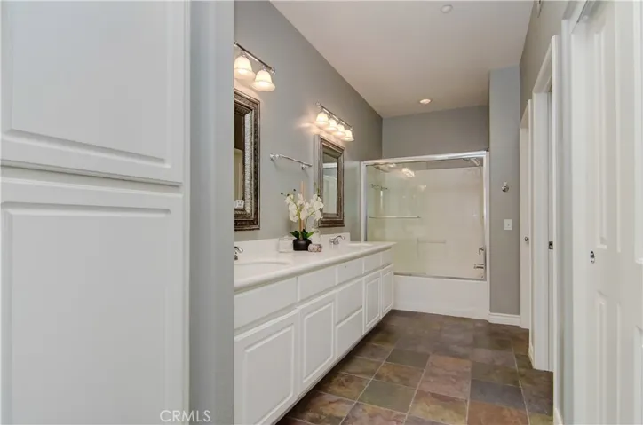 Spacious master bath has it all...dual sinks, lots of storage and stone flooring.
