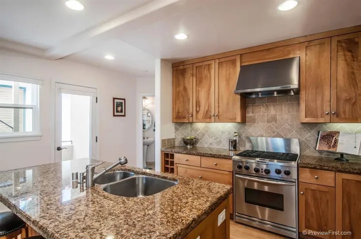 There are Bosch and KitchenAid stainless steel appliances in the kitchen with tumbled travertine backsplash.