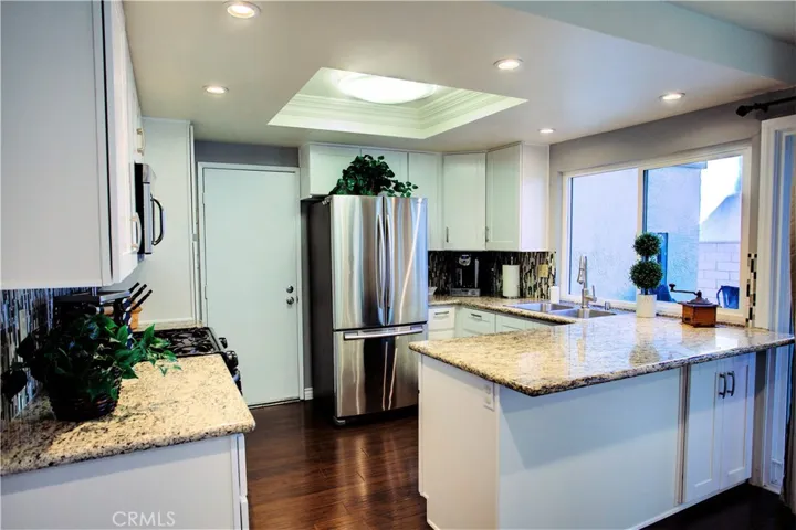 Beautifully upgraded kitchen with white shaker cabinets, granite counters, decorative backsplash, newer microwave, stainless steel appliances, recess lights, crown molding, dual stainless steel sink.