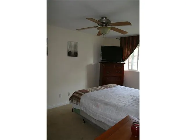 Spacious master bedroom with overhead ceiling fan and lighting. Generous closets with mirrored doors for addl lighting. View to lush backyard.