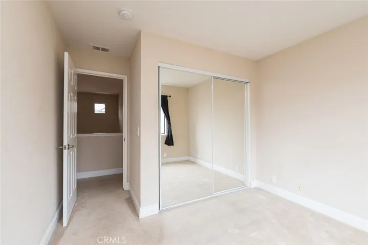 Upstairs bedroom with mirrored closet doors facing front of unit.