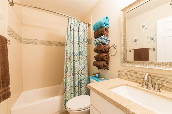 Hall bathroom with shower/tub combo, quartz countertop and modern tiled backsplash.