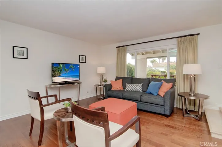Living room is flooded with natural light from large windows...beautiful hardwood flooring graces the home throughout the main level.