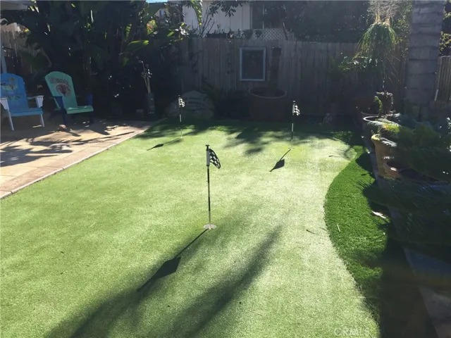 Fully fenced and gated front area of rear unit, features artificial turf with putting green.