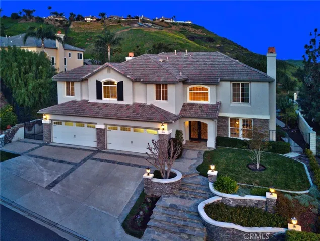An elevated street view of this magnificent estate with beautiful stone bordered stairs, walkways and planters.