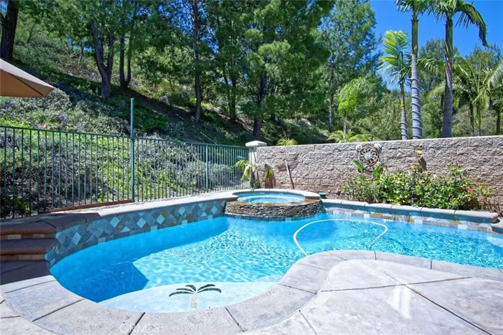 Pool with baja shelf and cascading waterfall from spa