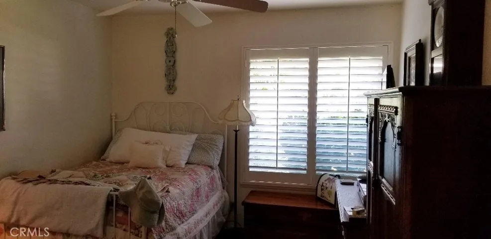 Secondary bedroom with fan and mirrored closet doors.