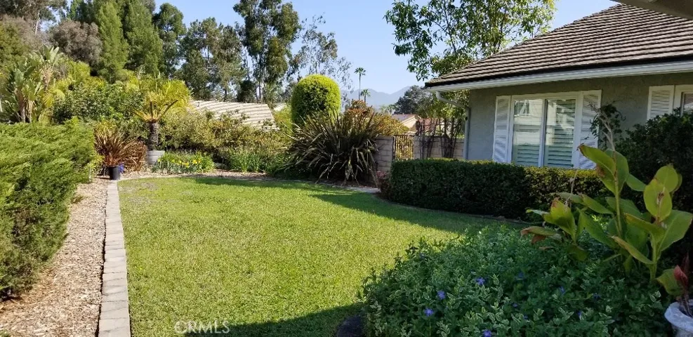 Lovely front yard with lots of flowers, bushes, and grass.