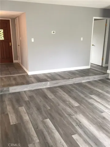 Living Room with First Bedroom and View Windows on Opposite Wall. Heavy Solid Wood Front Door in the Background.