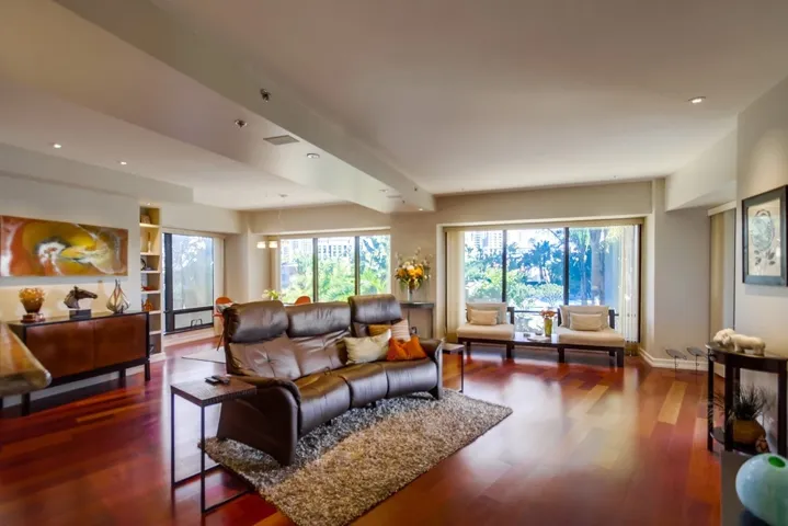 Spacious and open living area with glowing hardwood floors and custom in-ceiling lighting plan.  Colorful views of the skyline and lushly planted pool terrace wrap around this double corner layout. Views sweep from the north, east, and to the south.