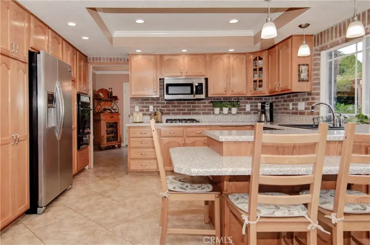 Remodeled kitchen features oak cabinetry, brick accents, metal hardware, and recessed lighting.