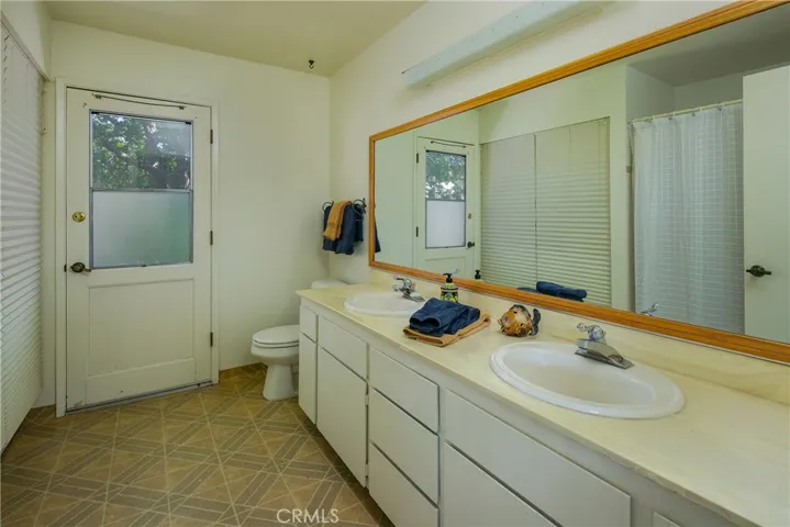 The hall bath has double sinks and a tub/shower. The laundry area is behind the shades. The door leads to the courtyard.
