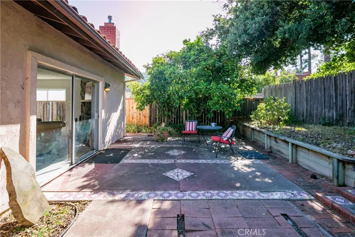 In the backyard, an orange tree fills the air with beautiful fragrance. Note the stairs at the bottom right of the photo that lead to the golf course.