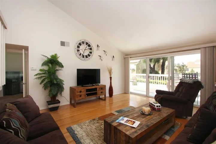 Living room with hardwood flooring and sliders to an enlarged deck to entertain family and friends.