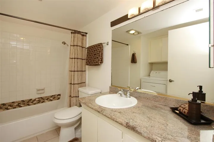 Bathroom with tub shower, granite counter top and washer and dryer.