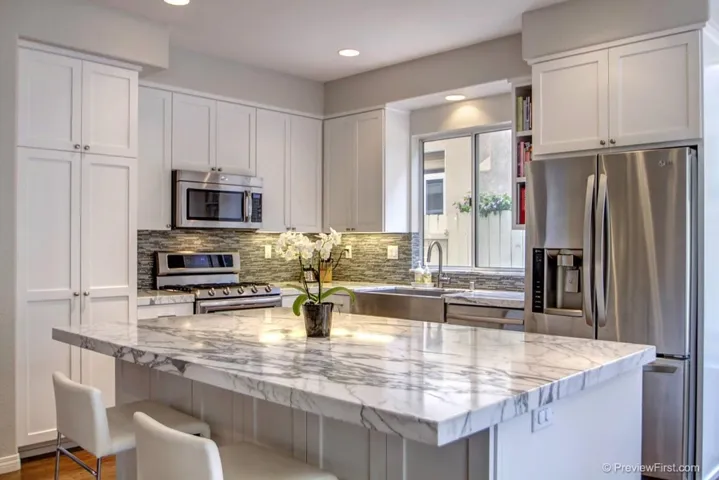 Gorgeous, modern kitchen features Statuario Marble counter tops, stainless farmhouse sink, stainless appliances, custom made cabinetry, great island with room for bar stools and open view to the family room, breakfast nook and backyard.