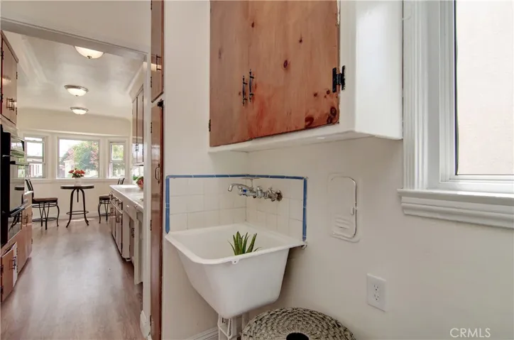 Separate laundry space has deep sink and extra cabinets.