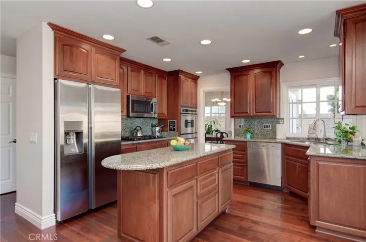 Remodeled kitchen has rich wood cabinetry, stainless appliances and large center island.